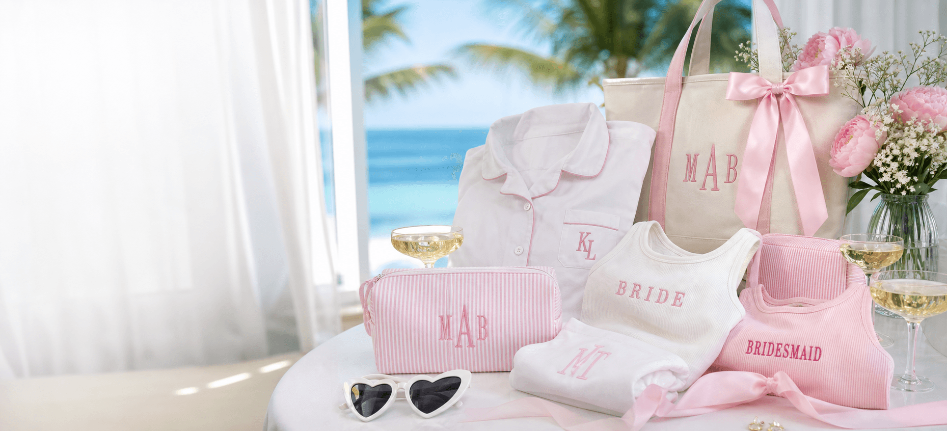 Monogrammed bachelorette weekend gifts with pink and white apparel, tote, toiletry bag, florals, and champagne