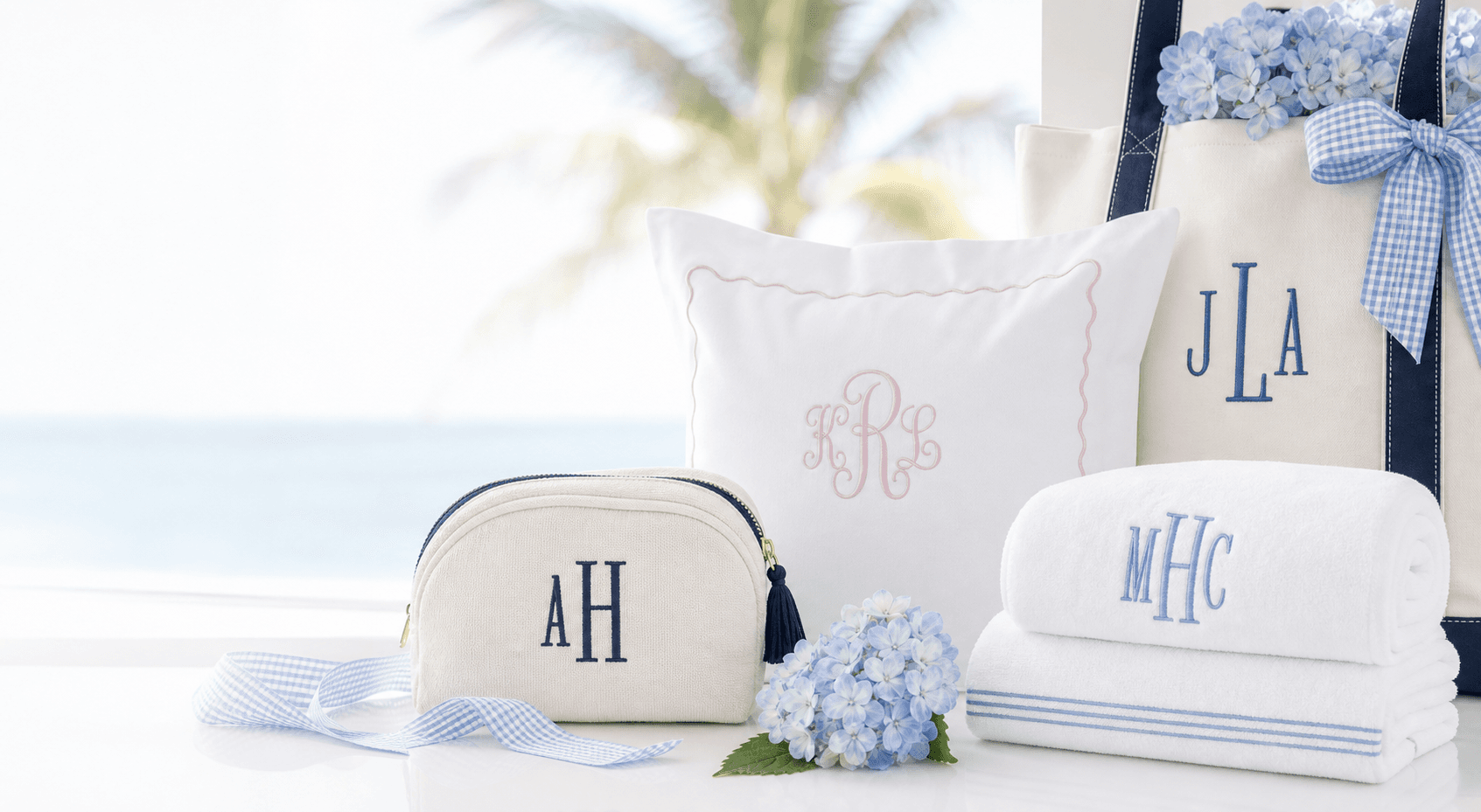 Cream pouch, monogrammed pillow, towels, tote, hydrangeas, and blue ribbon styled as custom gift ideas